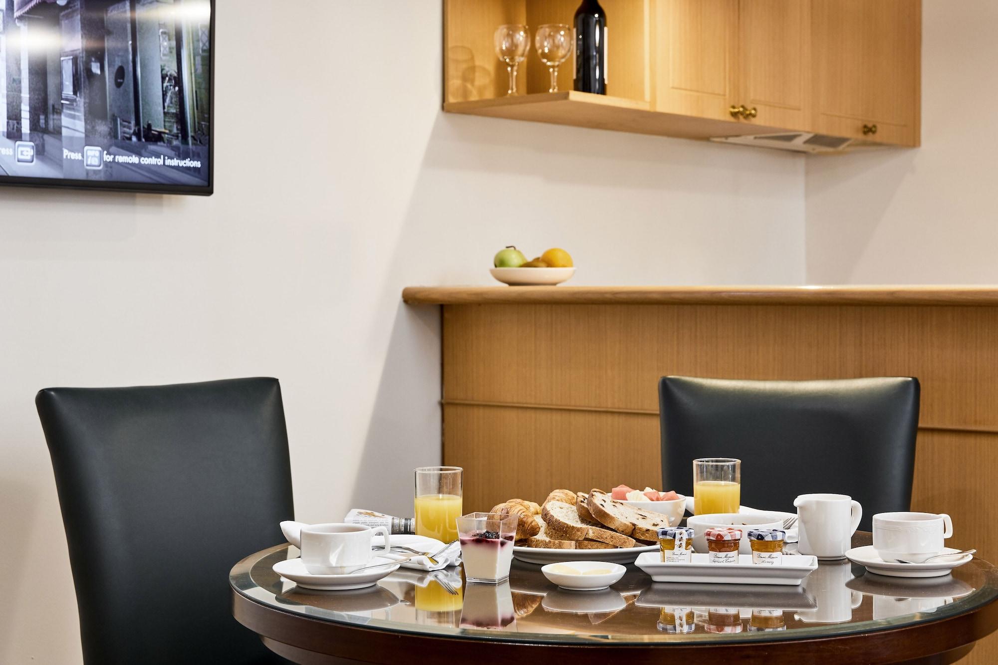 Hotel Stamford Plaza Melbourne Zewnętrze zdjęcie The photo shows a dining table set for breakfast or brunch. There are several food items displayed, including pastries and bread. Additionally, there are drinks, such as orange juice, served in glasses, and coffee in white cups. The table is round an