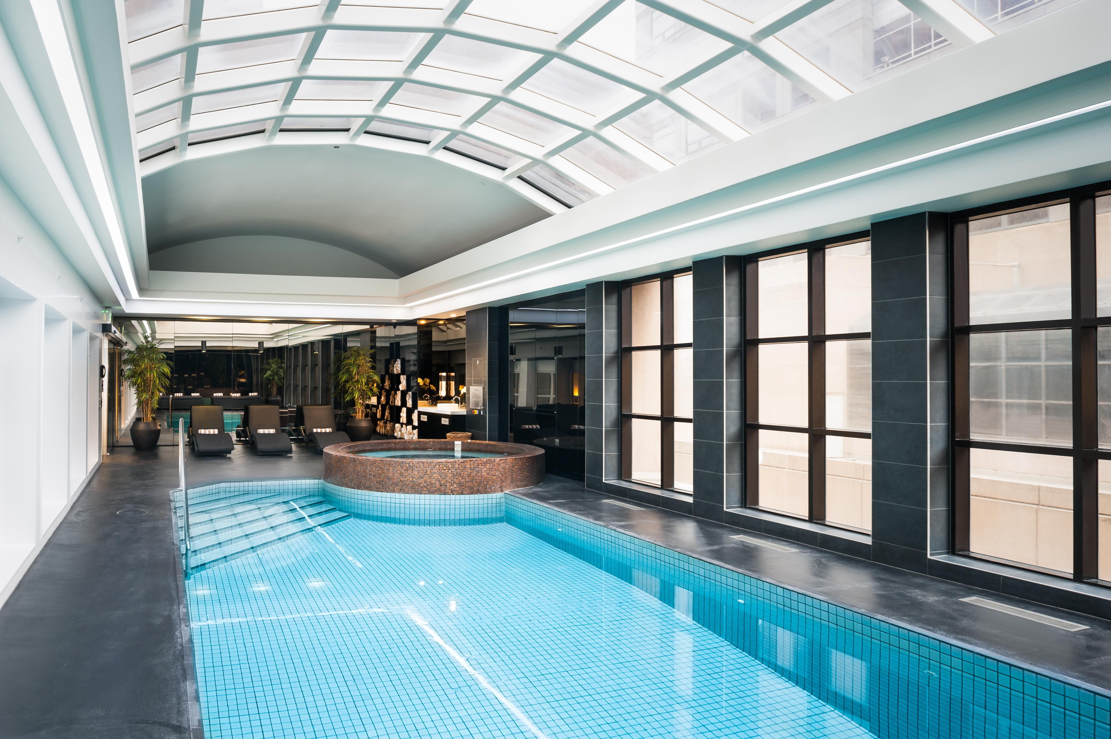 Hotel Stamford Plaza Melbourne Zewnętrze zdjęcie The photo shows an indoor swimming pool area with a modern and sleek design. The pool is rectangular and features bright blue tiles. Above the pool, there's a large, transparent glass ceiling that allows natural light to flood the space. Surrounding 