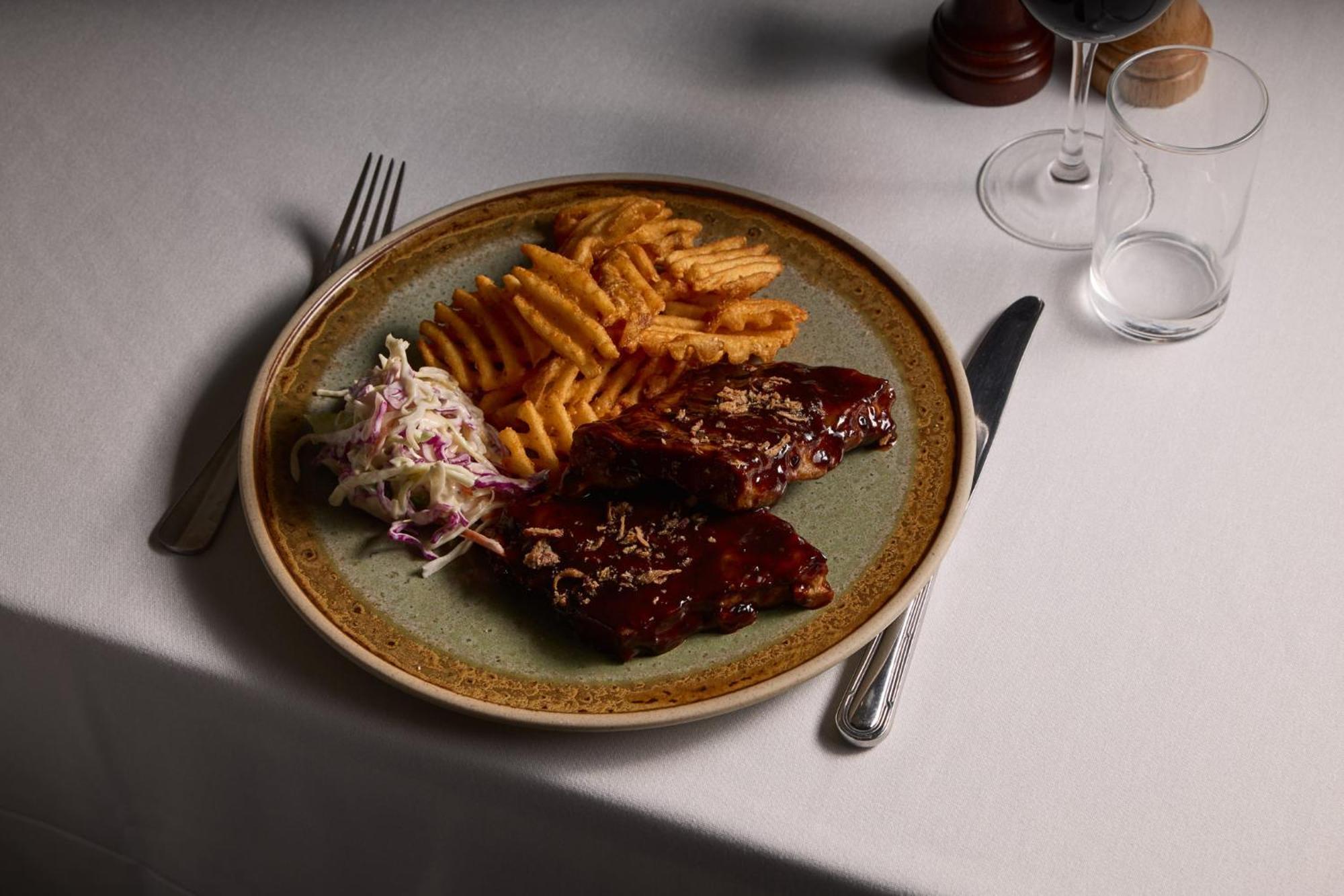 Hotel Stamford Plaza Melbourne Zewnętrze zdjęcie The photo displays a plate of food featuring two pieces of steak that appear to be glazed with a rich sauce. Alongside the steak, there are crinkle-cut fries arranged neatly on one side of the plate. Additionally, there's a small serving of coleslaw,