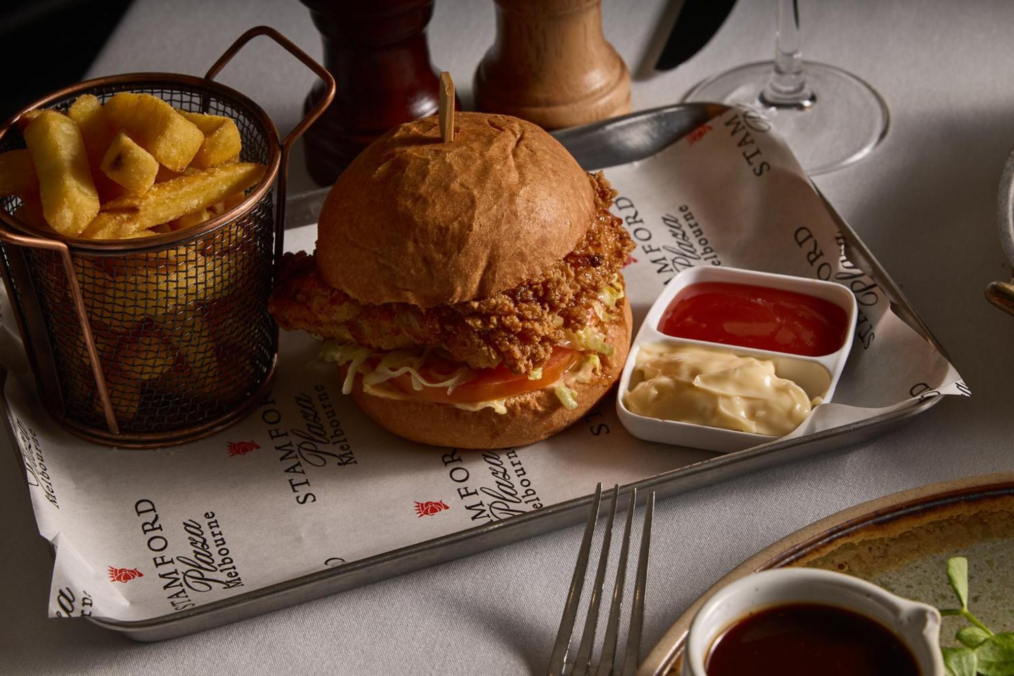 Hotel Stamford Plaza Melbourne Zewnętrze zdjęcie The photo features a meal served on a tray. In the center is a sandwich made with a golden-brown chicken fillet that appears crispy, placed inside a soft bun. The sandwich is likely complemented by some type of sauce or condiments underneath the chic