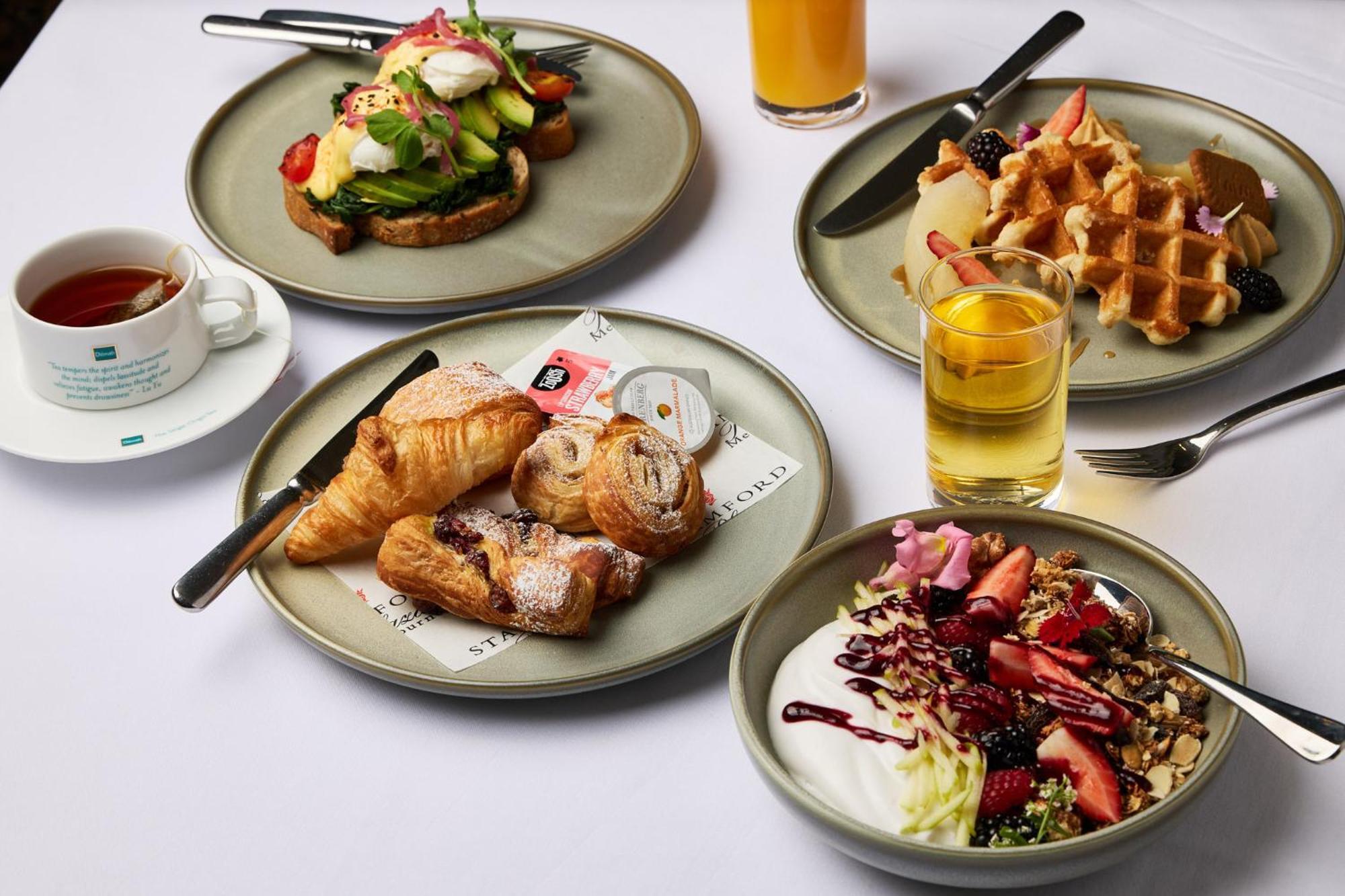 Hotel Stamford Plaza Melbourne Zewnętrze zdjęcie The photo displays a variety of breakfast items arranged on several plates. 

1. **Top-left Plate**: Features an open-faced sandwich with avocado, topped with poached eggs and garnished with vegetables.
2. **Top-right Plate**: Contains freshly made w