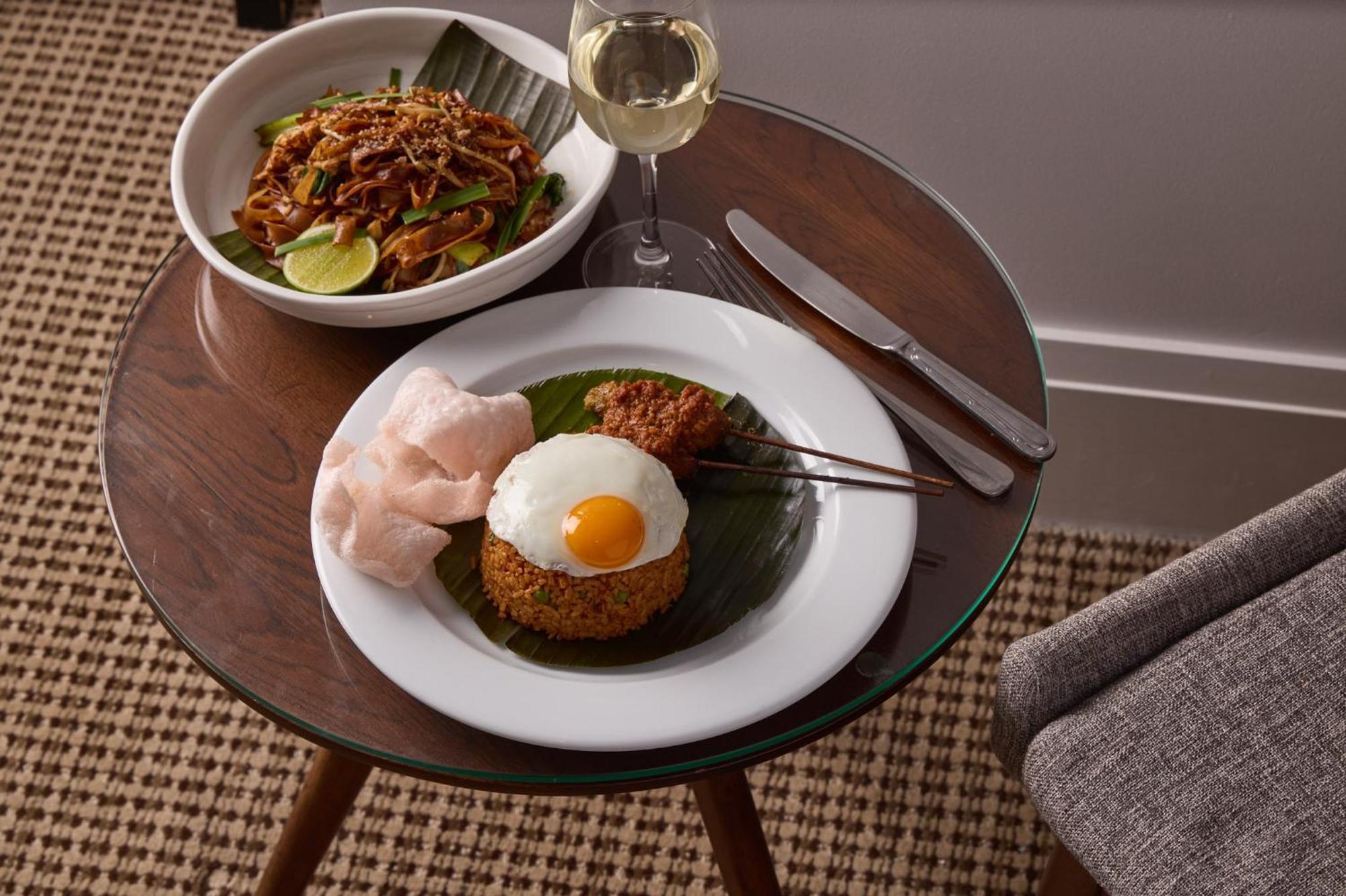 Hotel Stamford Plaza Melbourne Zewnętrze zdjęcie The photo shows a beautifully arranged meal on a wooden side table. On a white plate, there is a serving of fried rice, topped with a sunny-side-up egg, accompanied by prawn crackers. The dish also features a small portion of what appears to be a spi