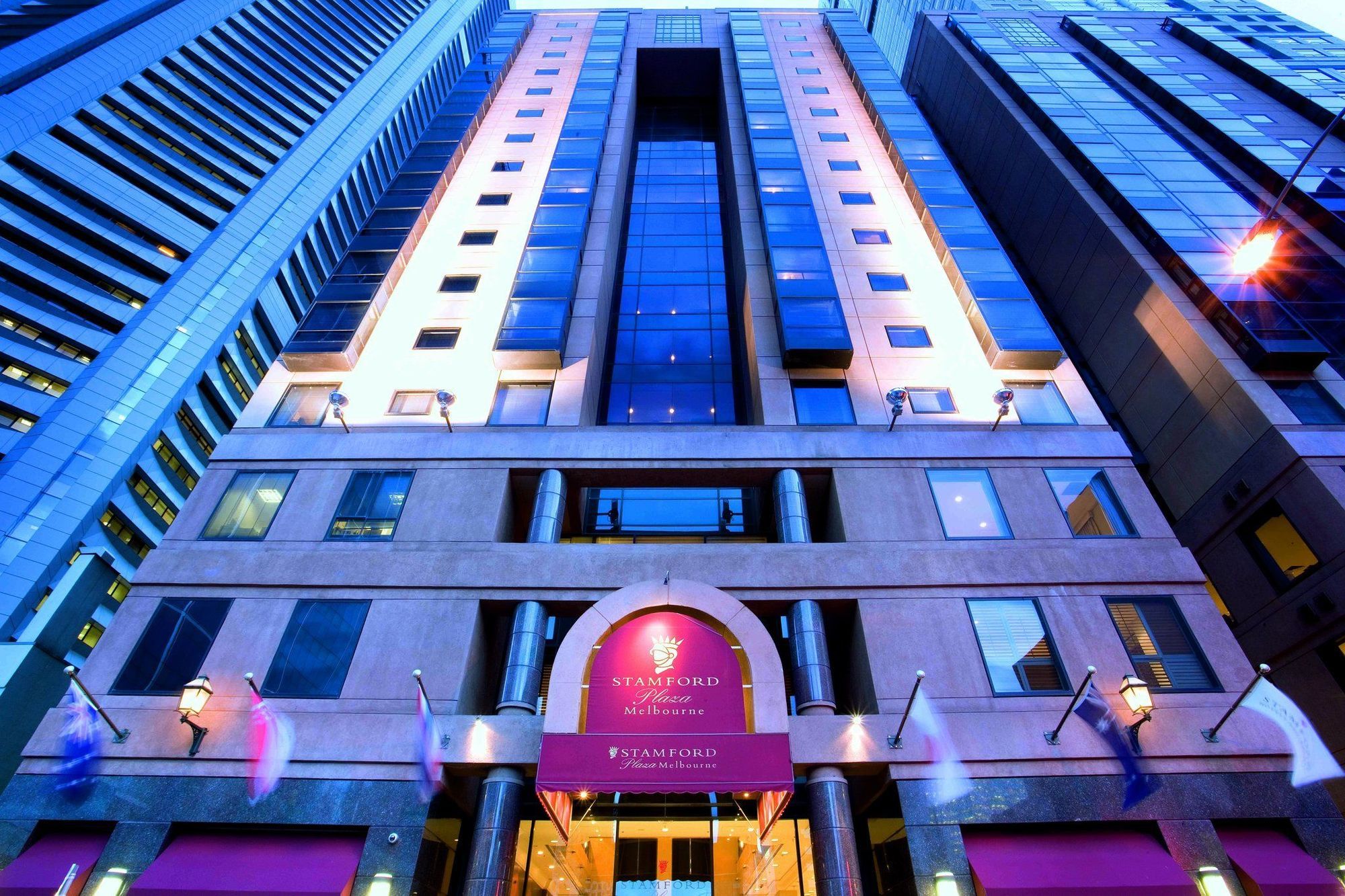 Hotel Stamford Plaza Melbourne Zewnętrze zdjęcie The photo shows the exterior of a hotel, likely a luxury or high-end establishment. The building features a modern architectural design with a combination of glass and stone. The entrance is marked by a prominent sign, and the facade is illuminated, 